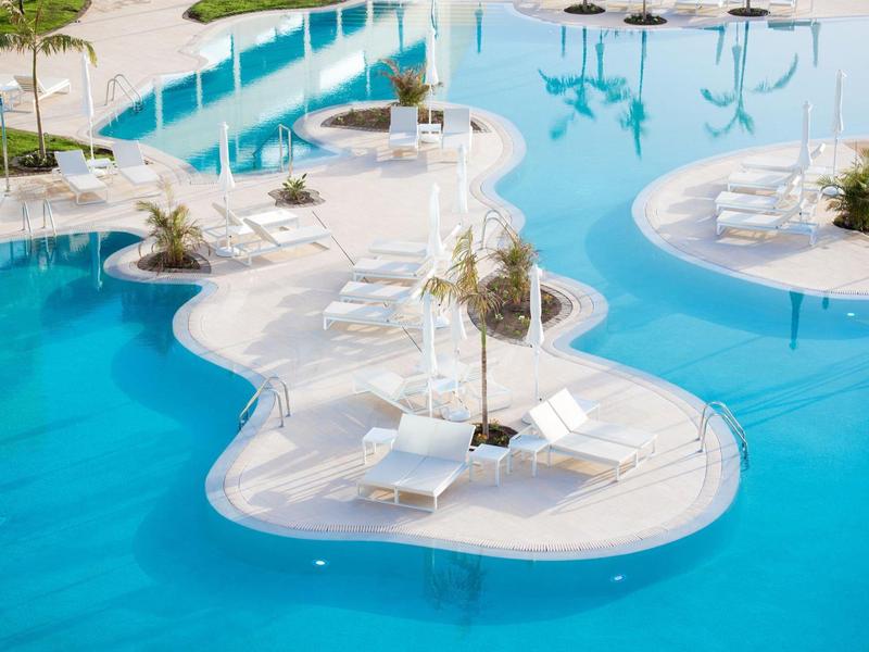 Zwembad met eilanden en ligstoelen bij een hotelresort.