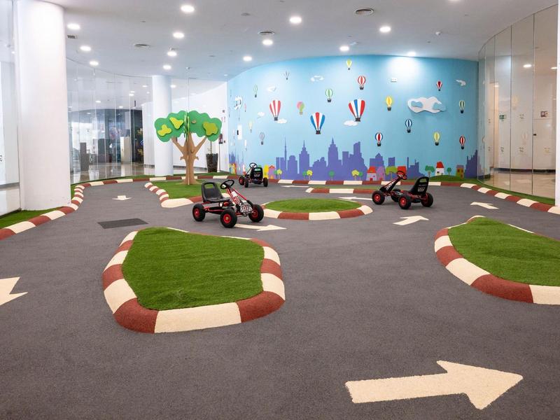 Binnenruimte met kleine speeltuin en elektrische voertuigen op een racebaan.