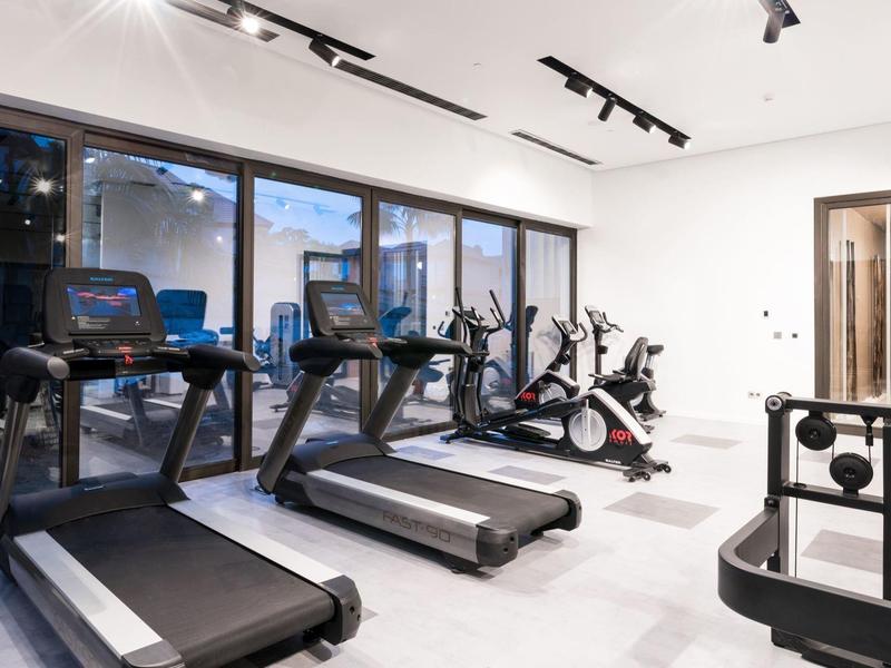 Moderne fitnessruimte met loopbanden en fietsen, grote ramen met uitzicht naar buiten.
