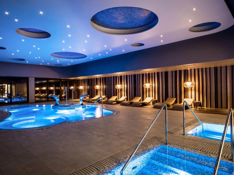 Modern overdekt zwembad met warm bubbelbad en gezellige verlichting in een hotel.