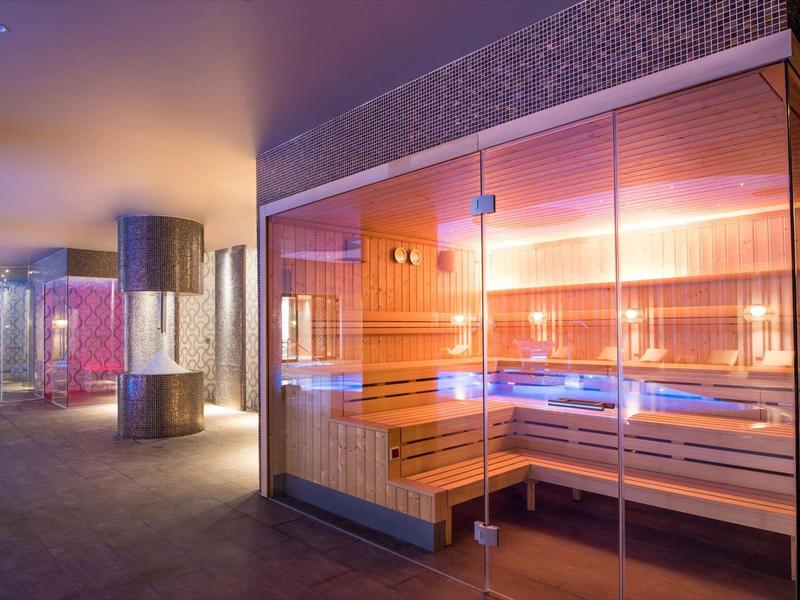 Moderne sauna met glazen wanden en warme verlichting in een ontspannen wellnessruimte.