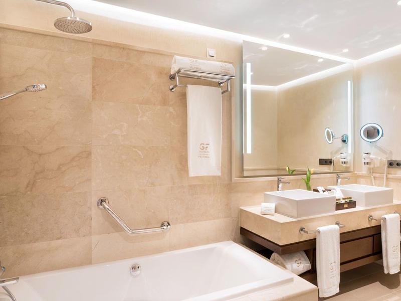 Moderne badkamer met bad, douchekop en dubbele wastafels in een lichte stijl.