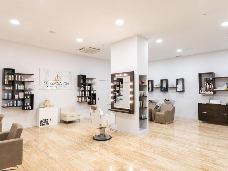 Helde, moderne kapsalon met stoelen, spiegels en planken aan de muren.