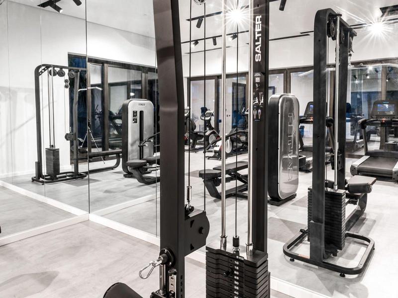 Moderne fitnessruimte met trainingsapparatuur en spiegelwand in een hotel.