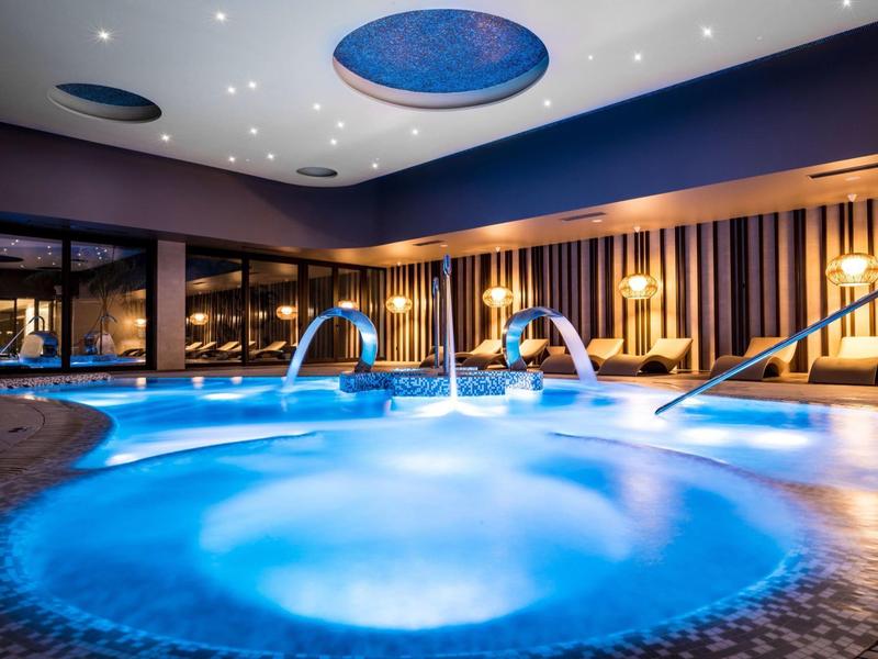 Binnenzwembad met verlichte whirlpool en ontspannende sfeer in moderne spa.