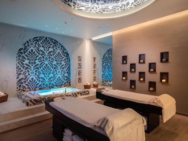 Modern spa met twee behandelbedden en decoratief verlicht wandpatroon.