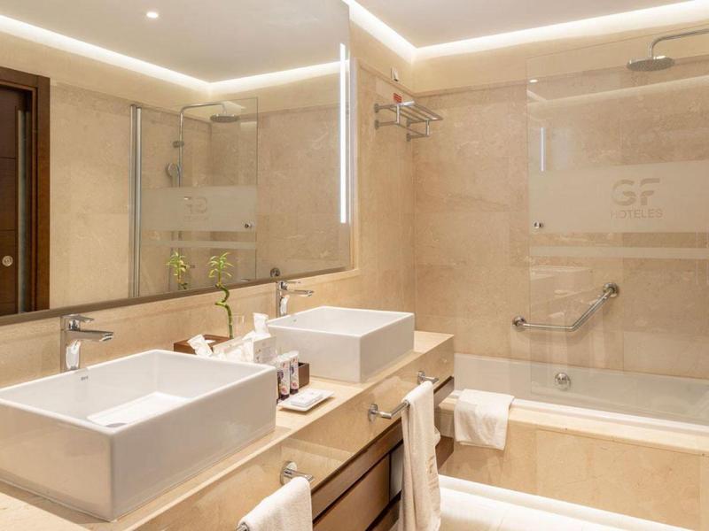 Modern badkamer met twee wastafels, grote spiegel en badkuip.