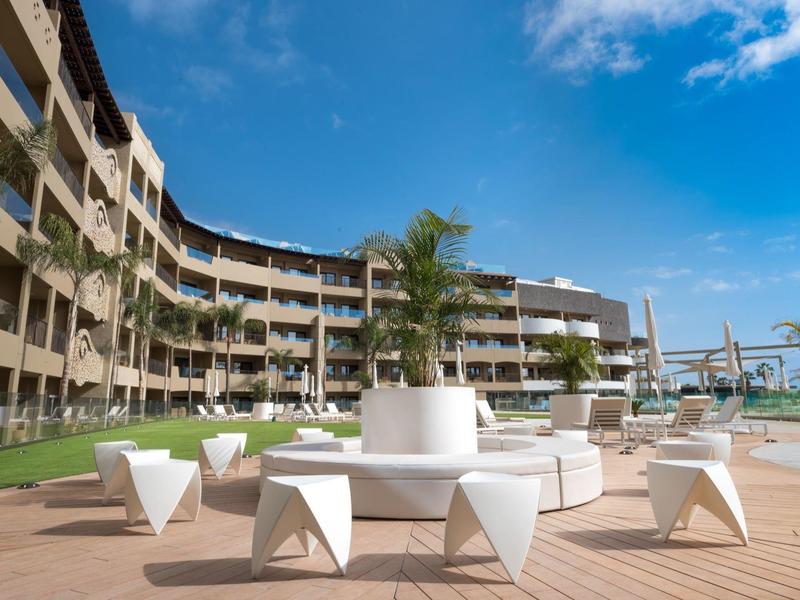 Moderne hotelterras met witte zitmeubelen, palmbomen en blauwe lucht