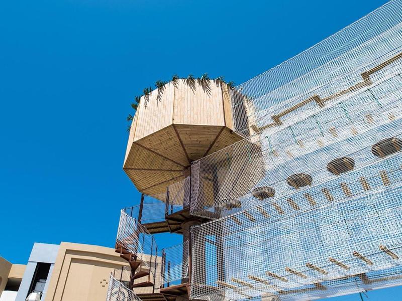 Moderne glazen gevel met een verhoogd, met bloemen versierd uitkijkplatform bij heldere lucht.