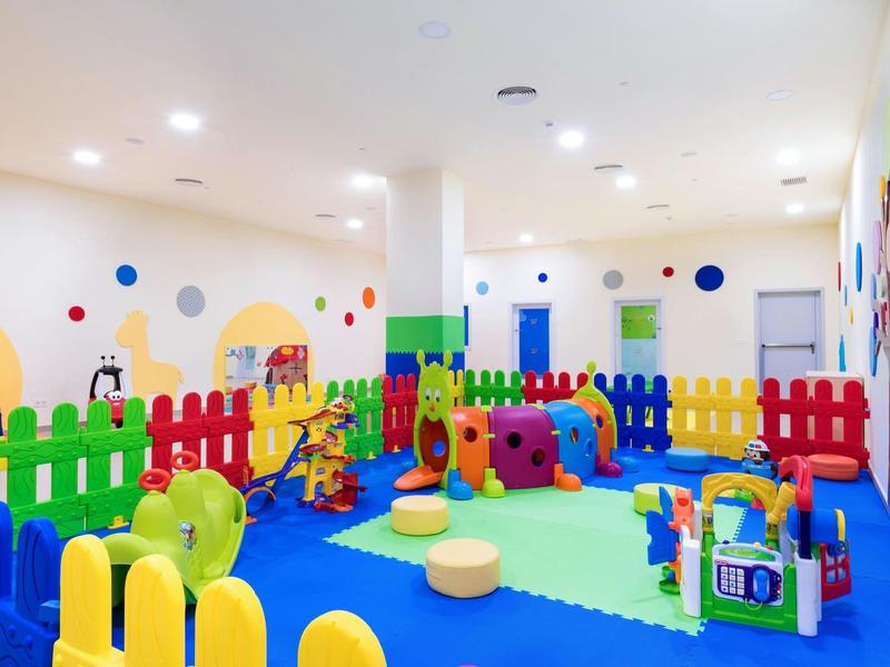 Kleurrijke speelkamer met speeltoestellen en zachte matten in een hotel.
