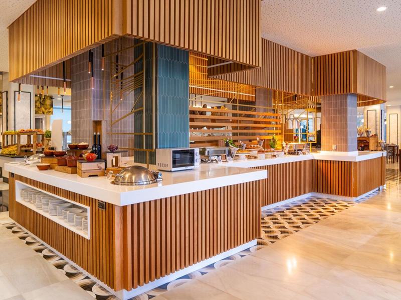 Modern hotel breakfast buffet with wooden counters and elegant lighting