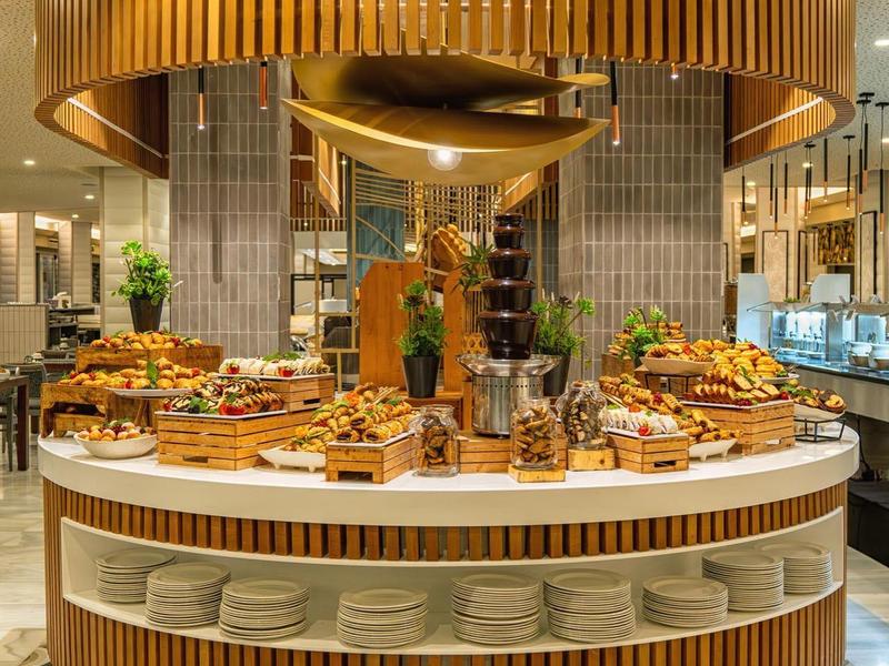 Round buffet table with various dishes and plates in a stylish restaurant interior.