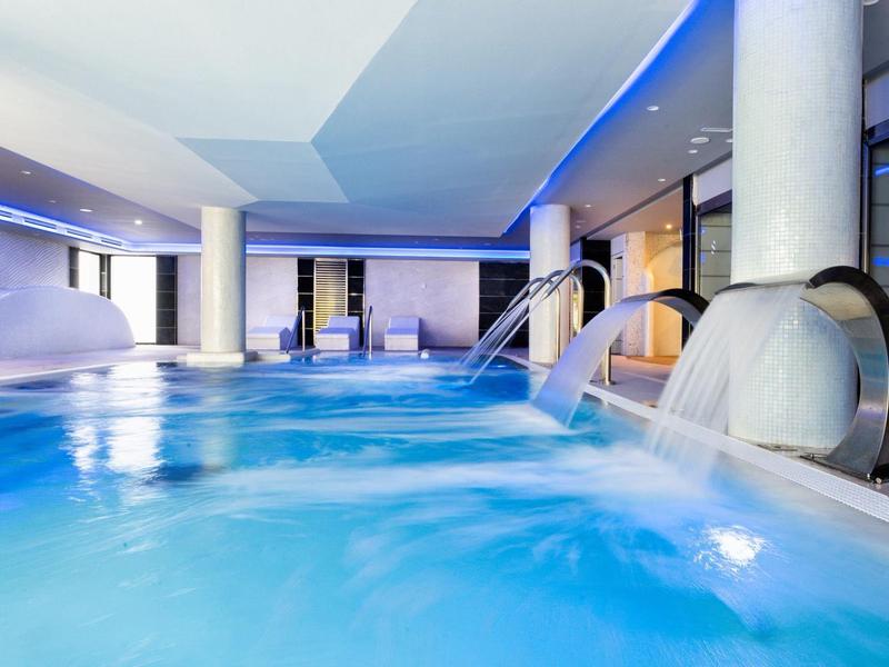 Indoor hotel pool with blue lighting and water features creating a relaxing atmosphere.