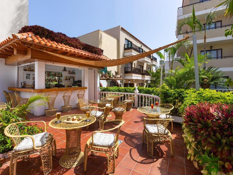 Gezellige buitenbar met rieten meubels en tropische planten op een zonnige dag.