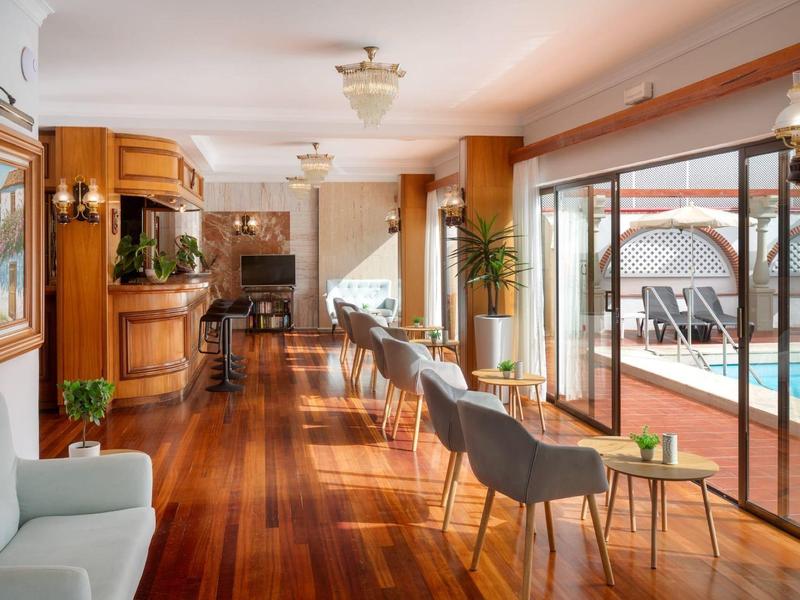 Elegante hotel-lounge met houten vloeren, comfortabele stoelen en directe toegang tot het zwembad.