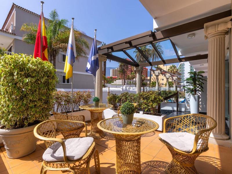 Gezellig buitenterras met rieten stoelen en tafels bij een hotel.