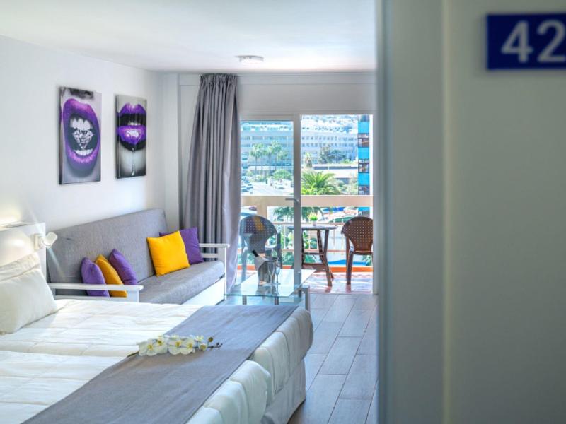 Chambre d'hôtel lumineuse avec deux lits, balcon et vue sur la mer.