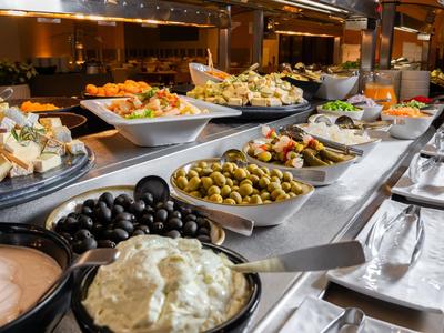 Buffet con diverse olive, insalate e salse in ciotole bianche su un bancone da cucina.