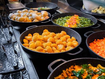 Diverse ciotole nere con verdure varie su un buffet.