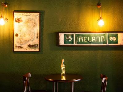 Angolo accogliente con due sedie, tavolo e luce calda su parete verde con decorazioni Irlanda.