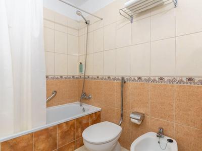 Piccolo bagno con vasca, doccia, WC e bidet, piastrelle chiare alle pareti.