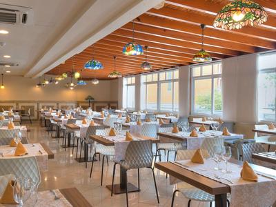 Ristorante moderno e luminoso con tavoli apparecchiati e grandi finestre.