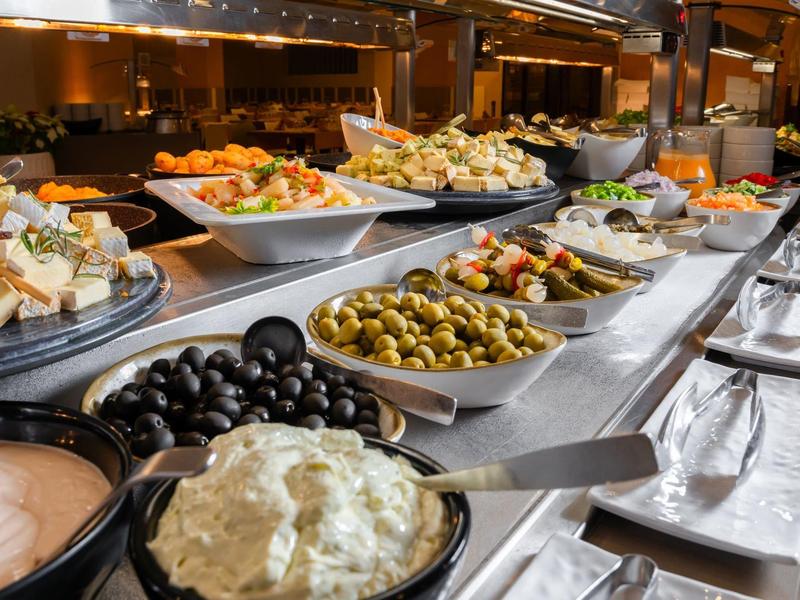 Buffet con diverse olive, insalate e salse in ciotole bianche su un bancone da cucina.