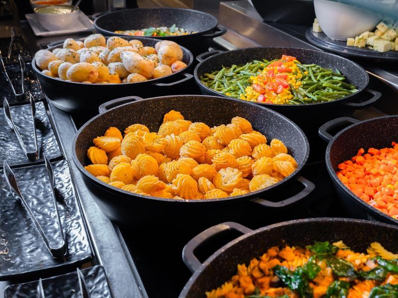 Diverse ciotole nere con verdure varie su un buffet.