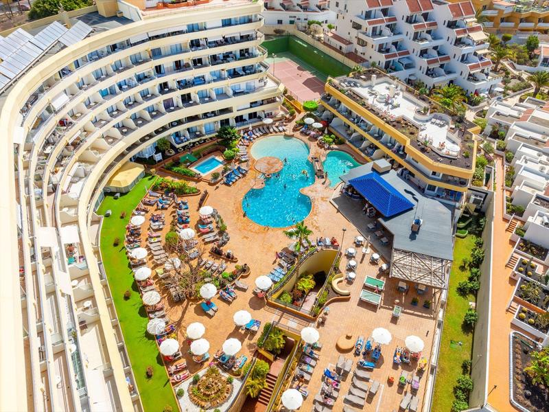 Grande piscina dell'hotel con ombrelloni e lettini circondata da edifici moderni