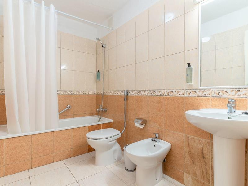 Bagno luminoso con vasca, tenda doccia, toilette, bidet e lavandino.