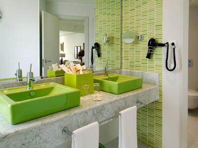 Nowoczesna łazienka z dwoma zielonymi umywalkami, marmurowym blatem i zieloną mozaikową ścianą.