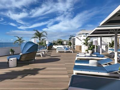 Luksusowy taras z leżakami, palmami i widokiem na morze pod niebieskim niebem.