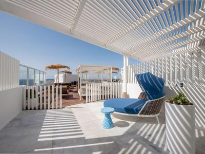 Balcone moderno con sedia a sdraio e vista mare sotto una pergola bianca.