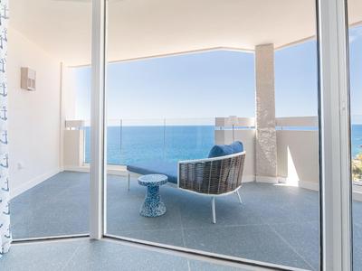 Balcone moderno con posti a sedere e vista mare limpida sotto un cielo sereno.