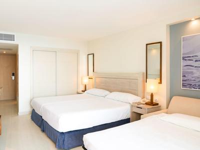 Pokój hotelowy z dwoma łóżkami, lampkami nocnymi i nowoczesnym jasnym wystrojem.