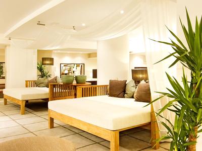 Heller, moderner Innenraum mit weißen Sofas und grünen Pflanzen in einem Hotel- oder Urlaubsbereich.