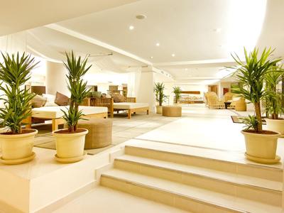 Heller, moderner Innenraum eines Hotels mit Treppen und vielen Topfpflanzen.