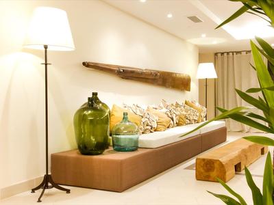 Modernes Hotelzimmer mit langem Sofa, Kissen und Dekoration aus Pflanzen und Licht.