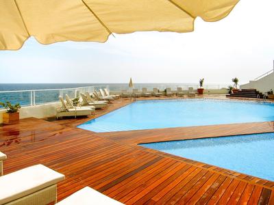 Basen na zewnątrz z drewnianym tarasem i widokiem na morze pod żółtym parasolem