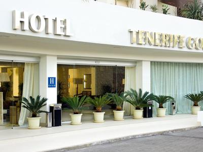 Wejście do hotelu z dużymi szklanymi drzwiami i kilkoma doniczkami z roślinami na zewnątrz.