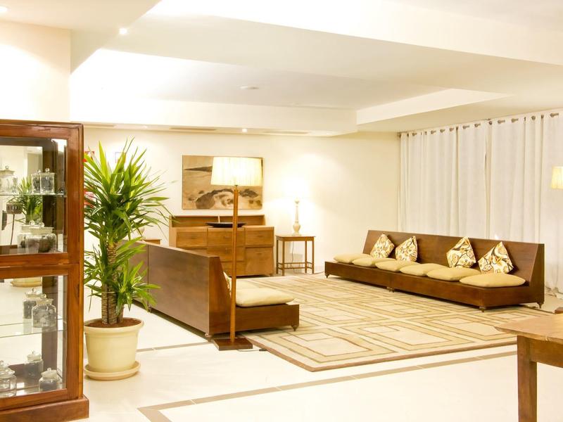 Przestronny hotelowy salon z drewnianymi meblami, roślinami i ciepłym oświetleniem.