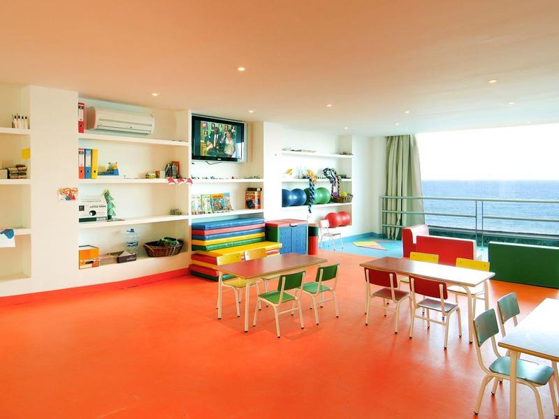 Jasna i kolorowa jadalnia z dużymi oknami z widokiem na morze.