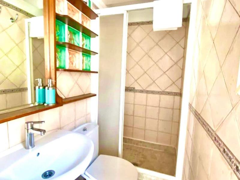 Bright bathroom with sink, mirror, shower cabin, and tiled walls.