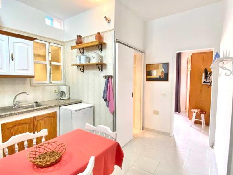 Bright kitchen with red tablecloth, white cabinets, and wooden shelves in a vacation home.