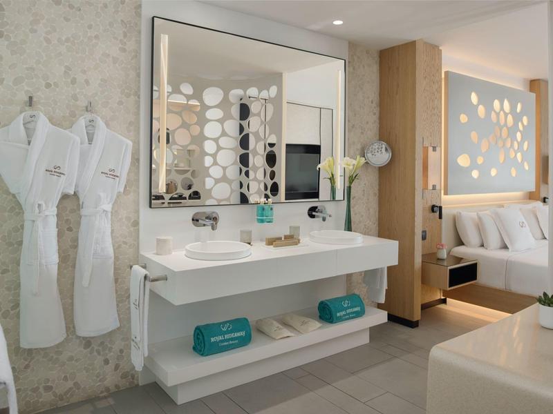 Moderní hotelová koupelna s dvojumyvadlem, velkými zrcadly a bílými župany