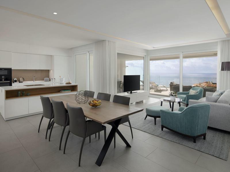 Modern apartment with dining area, kitchenette, and panoramic sea view windows.