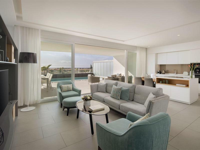 Bright living room with modern furniture and view of terrace and sea.