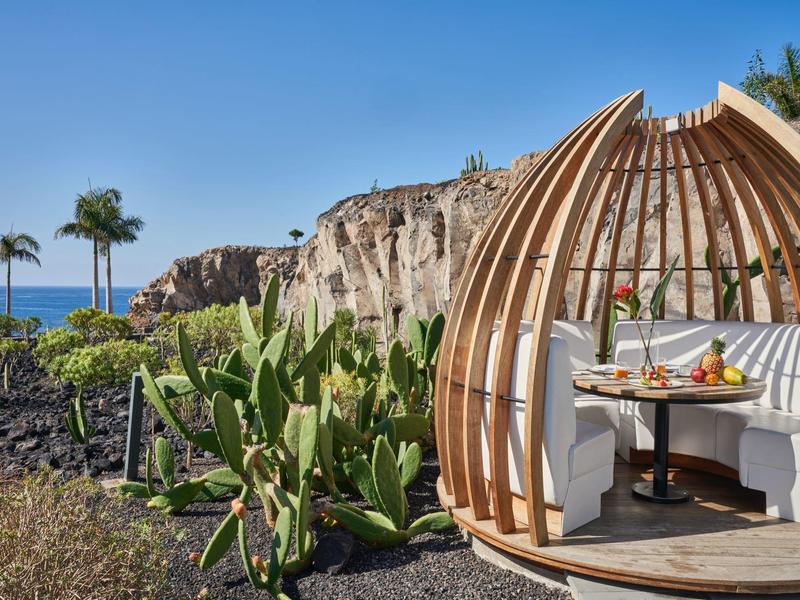 Cozy wooden cabin with seating in tropical garden landscape overlooking the sea.