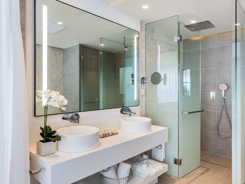 Modern bathroom with sink, large mirror, and glass shower.