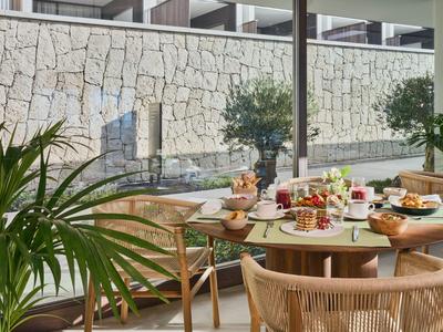 Taras z nakrytym stołem śniadaniowym i roślinami przed kamiennym murem